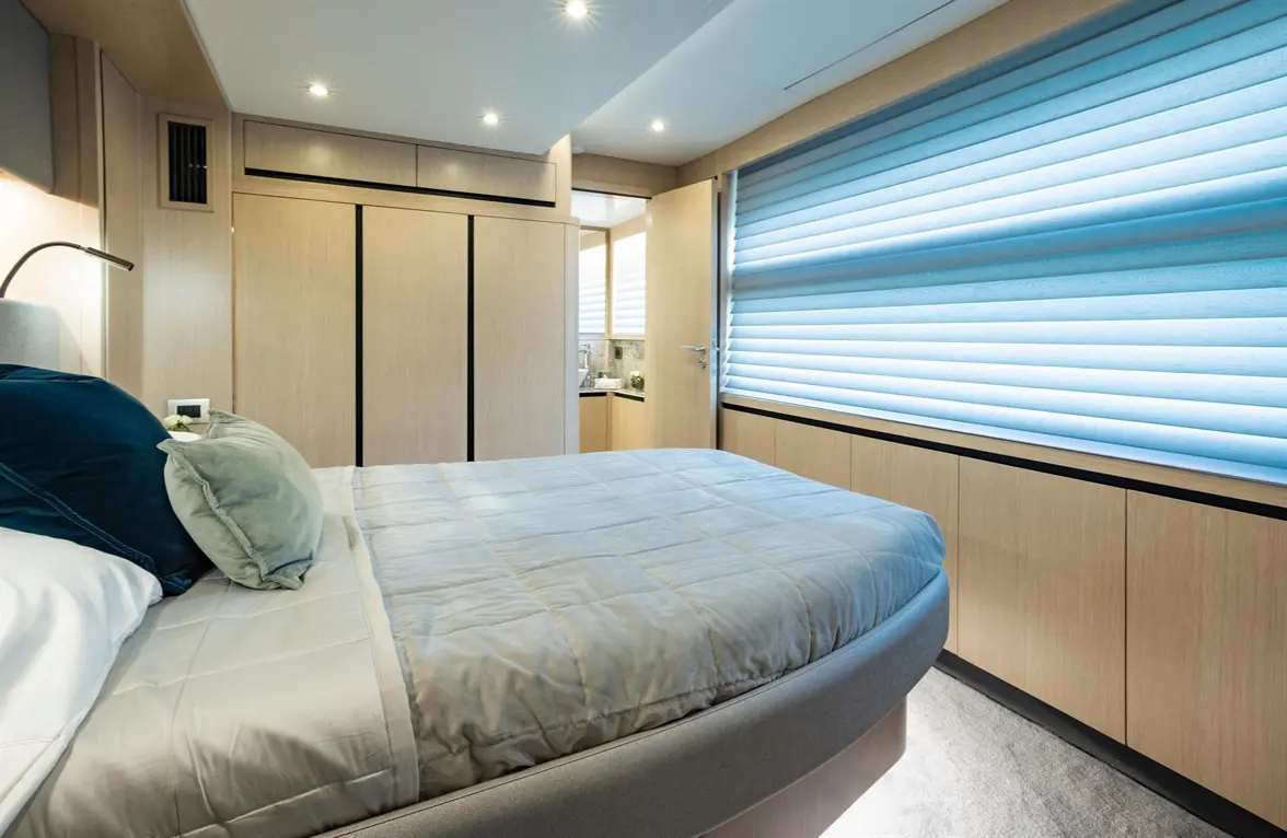 Stylish bedroom featuring a double bed with plush pillows, wooden cabinetry, and light-filtering shades for natural light.